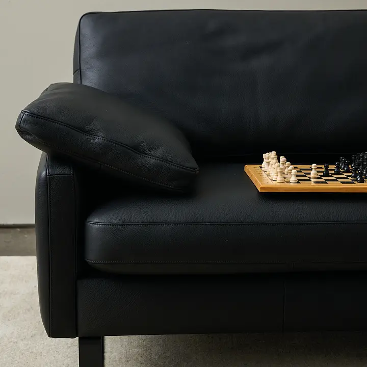 Schwarzes Ledersofa mit Kissen und Schachbrett auf der Sitzfläche